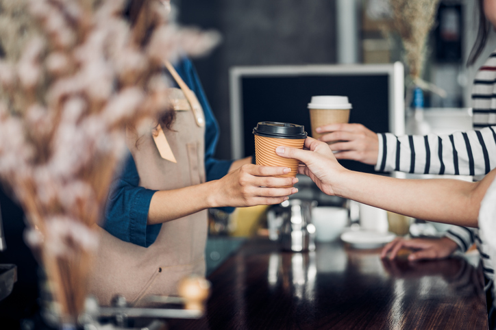 A boutique cafe, handing over freshly made coffee to a customer